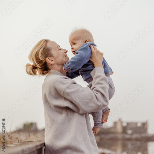 Billede på lærred Tender woman caressing her little baby boy infant child outdoors on autumn trip to Secovlje salinas landscape park, Slovenia
