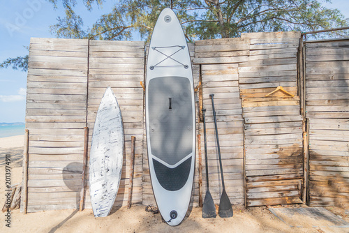 Valokuva The surfboard leaned against the wooden wall by the sandy beach.