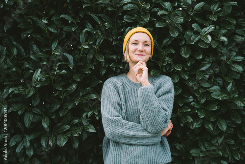 Obraz na plátne Photo of friendly smiling attractive woman on background of green hedge