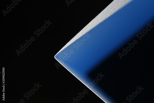 Canvastavla Cartulina en forma de triángulo con luz azul y bordes blancos con un fondo negro