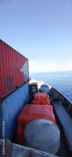 Bright red and blue shipping containers are secured on the deck of a cargo boat