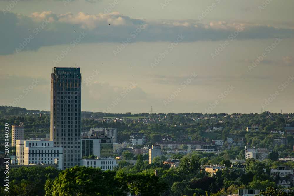 Fototapeta premium Modern skyscraper rising above Krakow cityscape during golden hour