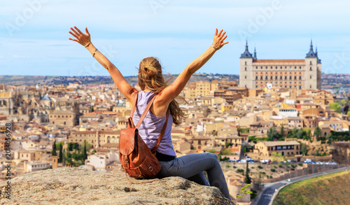 happy woman traveler with arms outstretched enjoying the panoramic view of Toledo, Spain