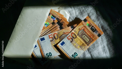 Cuadro en lienzo Stack of 50 euro banknotes partially hidden in envelope under dramatic shadow