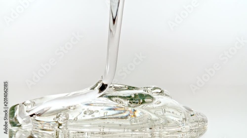 Macro shot of Clear Cosmetic Gel, Fluid, Serum Pours from Above on a White Glass Surface. Closeup Organic Products, Medicine. Dermatology Science Laboratory. High quality 4k footage
