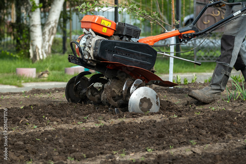Konstfotografi Gardening worker tilling ground with power tiller in spring season