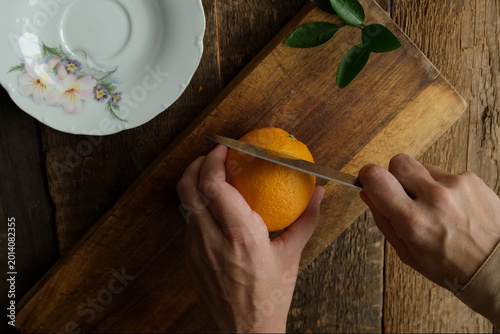 Fotografía Hands slicing fresh oranges on wooden cutting board