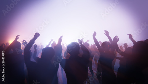 Fotografie Energetic crowd enjoying a music concert with hands in the air and bright stage