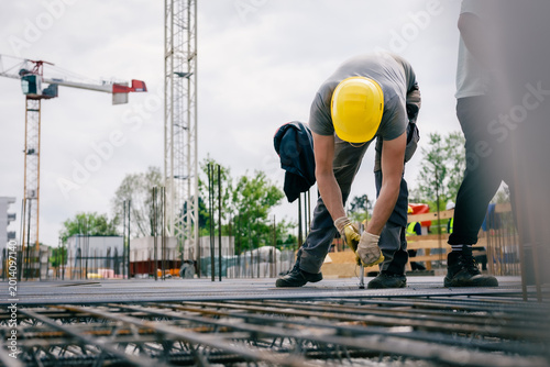 Eisenflechter mit Zange auf Baustelle 
