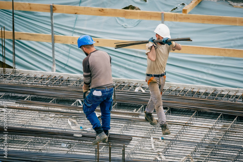 Cuadro en lienzo Bauarbeiter trägt Eisenstangen auf Baustelle