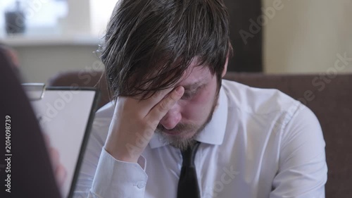 Man showing stress in a meeting at an office while discussing important matters with a colleague