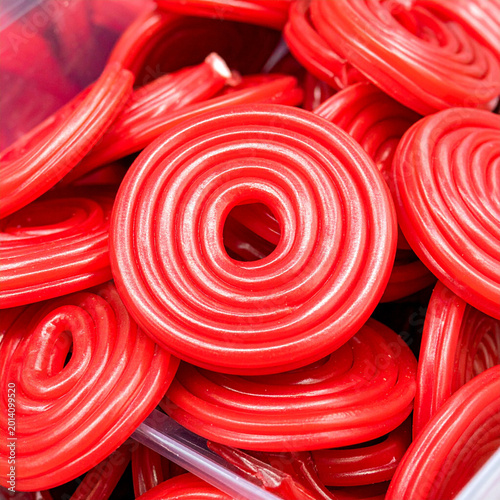 macro photograph of a bulk candy bin filled with red licorice wheels in a store. Ai