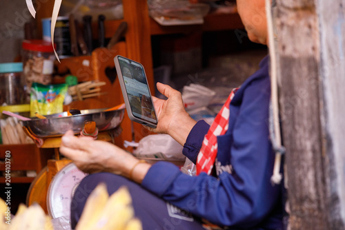 Tableau sur toile Market vendor using smartphone, absorbed in mobile screen, focused smartphone user, close up
