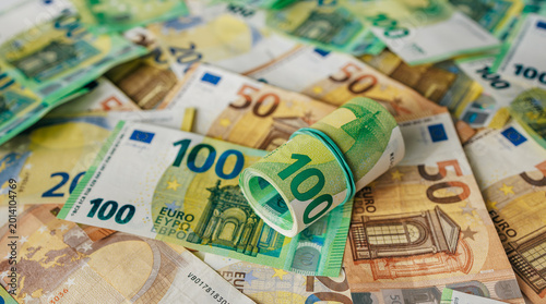 Принти на полотні Macro close-up of rubber-banded 100 euro bills placed over mixed denomination euro banknotes