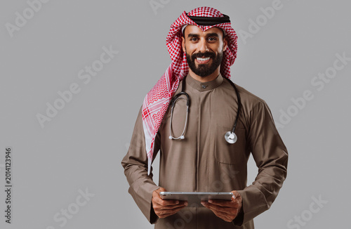 Bild auf Leinwand Saudi arabian doctor smiling, holding digital tablet for healthcare