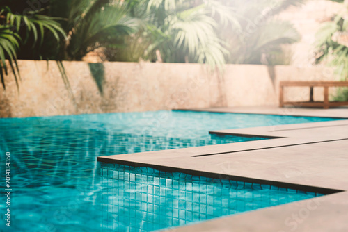Luxury pool closeup edge with granite tiles and tropical garden. Summer travel hotel resort. Poolside product placement for beauty brand display. Modern aesthetic architecture design.