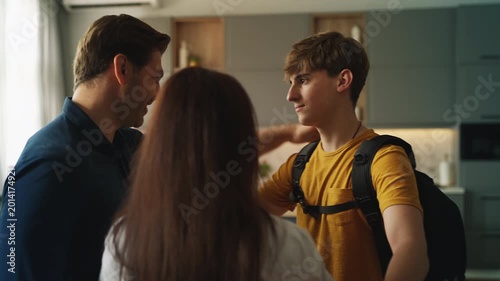 Teenage son hugging his parents before leaving for college, family support