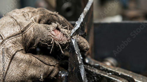 Torn Protective Work Glove Exposed to Sharp Metal Edge Showing Workplace Injury Hazard