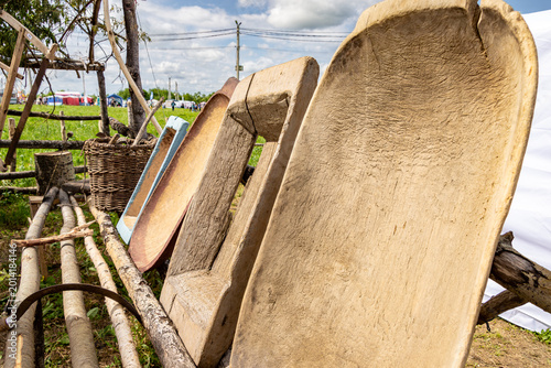 Photos Exhibition of carved wooden troughs and wicker basket on birch log stand with fe