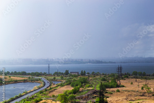 Rainstorm over lake and industrial cityscape