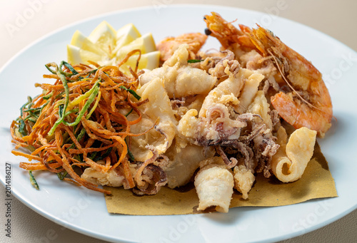 Bild auf Leinwand Close up of mixed fried seafood with calamari shrimp crispy vegetables and lemon served on white plate in Italian Mediterranean cuisine
