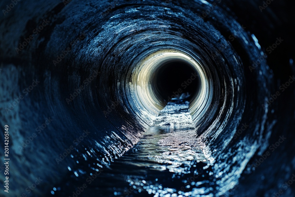 Fototapeta premium Dark underground sewer tunnel with industrial wastewater flowing through a round concrete pipe at night