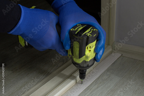 Fotografi Hands using cordless drill to install door threshold indoors