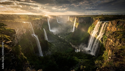 Majestic Waterfalls Cascade Through Lush Canyon Under Dramatic Sky