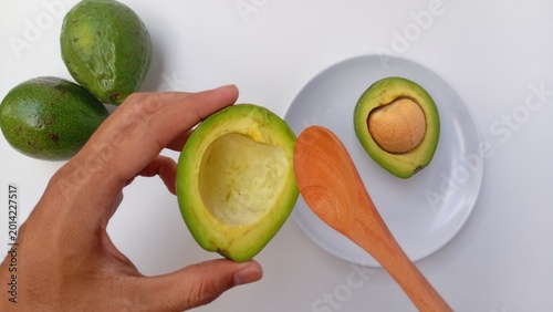 Фотография Her hand held half a fresh avocado with the pit removed, next to it was the othe