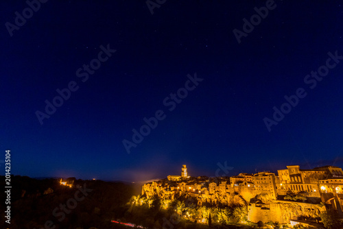 Starry sky. Nighttime view of city with clock tower and street light, Sovana, Tuscany, Italy, long exposure motion blur