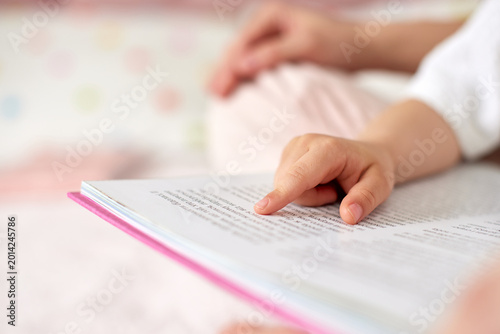 Child's hand with pointing finger reading a storybook, engaging with written text, symbolizing early education and literacy