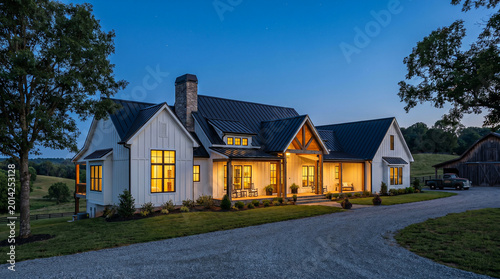 Modern farmhouse architectural design featuring white board and batten siding with dark metal roof at sunset twilight hour.