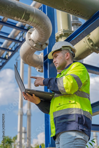 Industry specialists inspect massive piping at a gas-fired power plant integrated with a petroleum and oil refinery complex, focusing on maintenance for energy generation safety and efficiency.