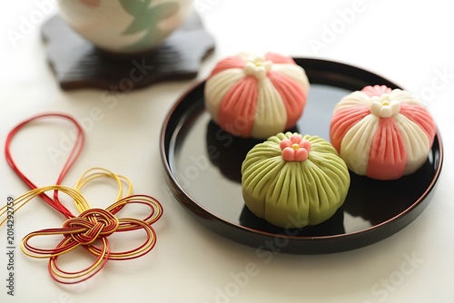Japanese wagashi sweets displayed on a dark plate with traditional decorations
