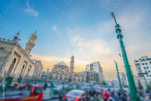 A scenic view of an ancient mosque with minarets at the historic Khan el-Khalili market in Cairo, Egypt, during a golden sunset.