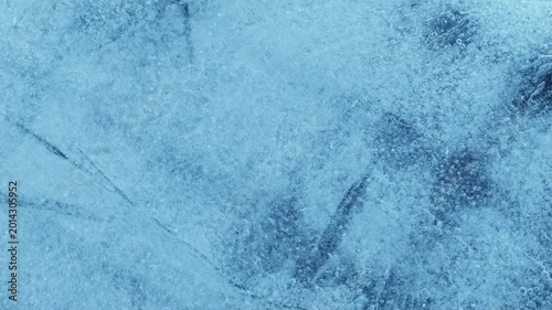 Extreme macro close-up of cracked blue melting ice texture in time lapse. Abstract frozen water surface with translucent crystal patterns, condensation and thawing details in studio lighting.