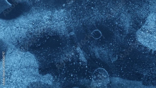 Extreme macro close-up of cracked blue melting ice texture in time lapse. Abstract frozen water surface with translucent crystal patterns, condensation and thawing details in studio lighting.