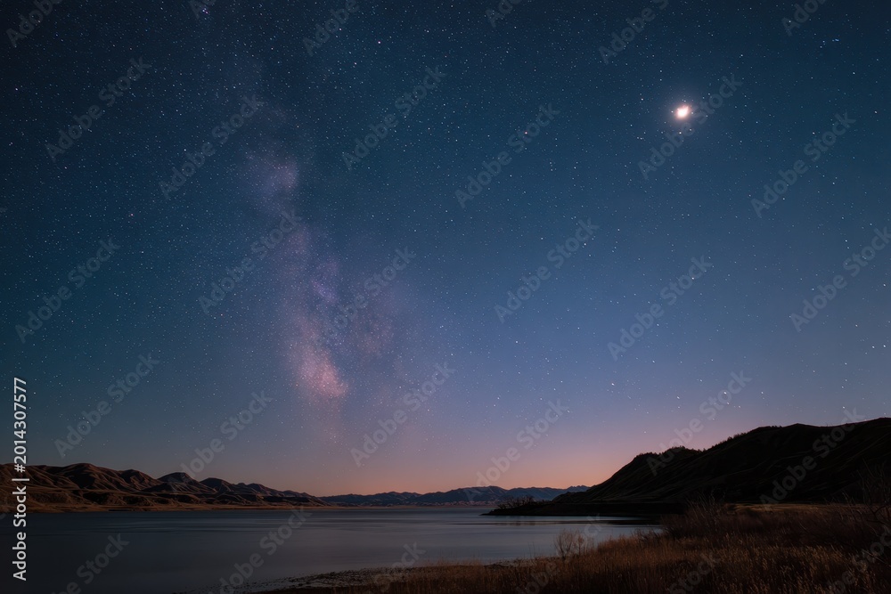Fototapeta premium Peaceful Night Scene: Crescent Moon and Stellar Field Over Calm Water