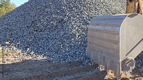 Heavy machinery moves gravel at construction site in sunny weather
