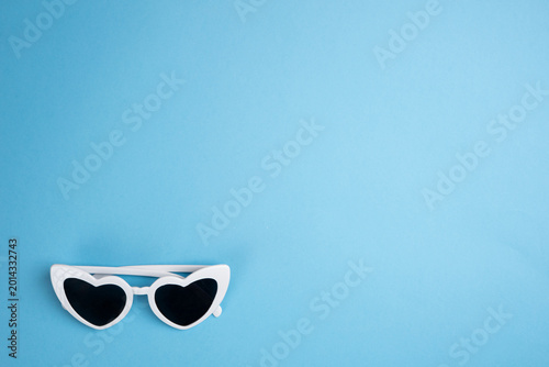 White heart-shaped sunglasses on a light blue background