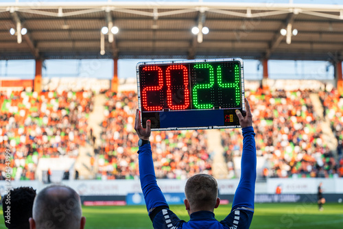 Foto Rear view of a fourth official holding an electronic substitution board showing numbers 20 and 24 at a football stadium