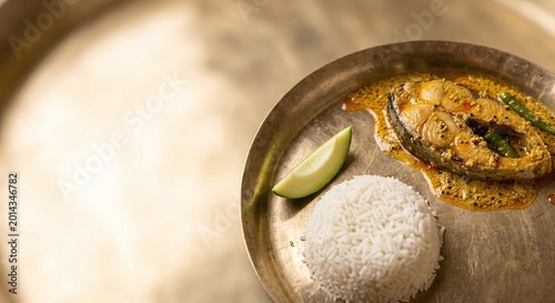 Traditional Bengali Ilish Maach Bhapa with Steamed White Rice and Sliced Green Mango on Brass Plate