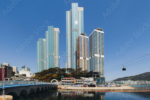 Songdo beach, Busan, South Korea with Songdo Cloud Trails Walk pedestrian bridge, sandy beach and Turtle island view, sunny day with blue sky, Songdo Skywalk and Geobukseom Island and Busan Air Cruise