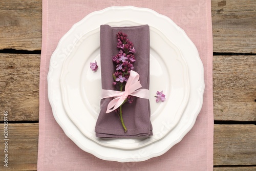Foto Stylish setting with plates, napkins and flowers on wooden table, top view