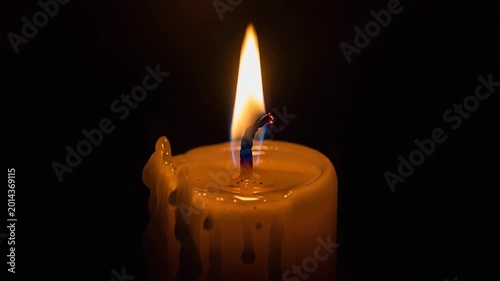 Candle flame burning with melting wax on dark background  
