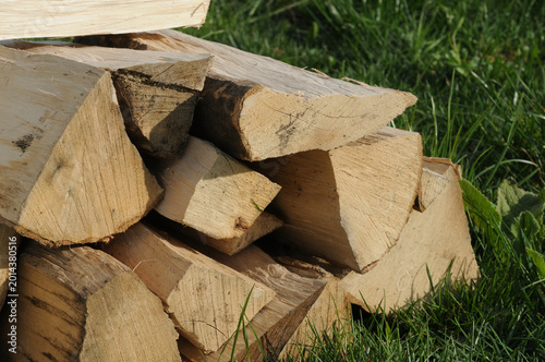 Firewood stacked in a pile on green grass background. Pile of firewood.