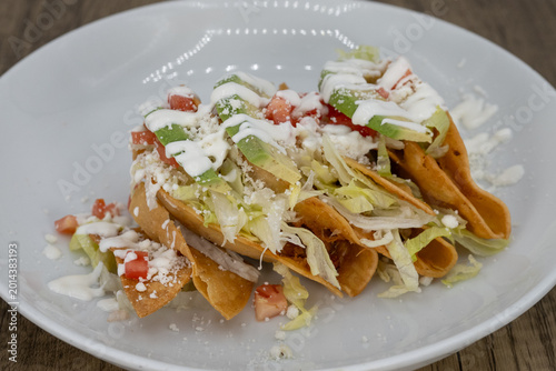 Bild auf Leinwand Hearty plate of potato tacos smothered in sour cream, lettuce, and feta cheese t