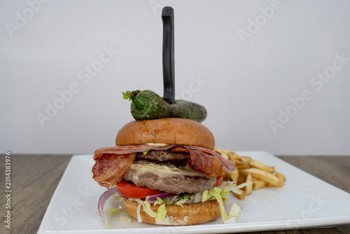 Photography Hearty Mexican burger stacked thick with hamburger, ham, vegetables, and topped