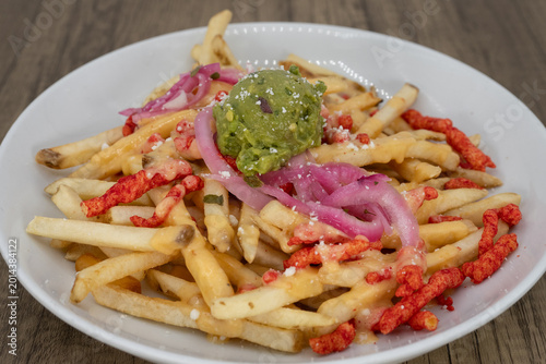 Slika na platnu Hearty plate of crispy spicy french fries smothered in guacamole and feta cheese