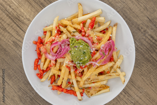 Billede på lærred Overhead view of hearty plate of crispy spicy french fries smothered in guacamol